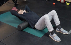 Dr. Jon laying over the foam roller in his middle/upper back, relaxing to mobilize his spine